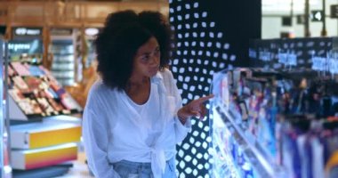 Pleasant African American young woman in white casual shirt and blue denim jeans, shopping for groceries in supermarket