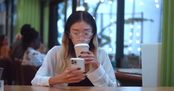 Asian Woman Eyeglasses Sitting Cafe Scrolling Smartphone App Using Mobile — Video Stock