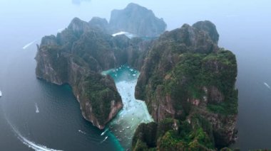 Sinematik hava manzaralı tropikal ada Ko Phi Phi Lee ikonik Maya Körfezi ve Pileh Lagoon ile Tayland 'daki Phi Phi adalarındaki kayalıkları çevreledi. Denizdeki güzel doğal tropikal ulusal park adası.