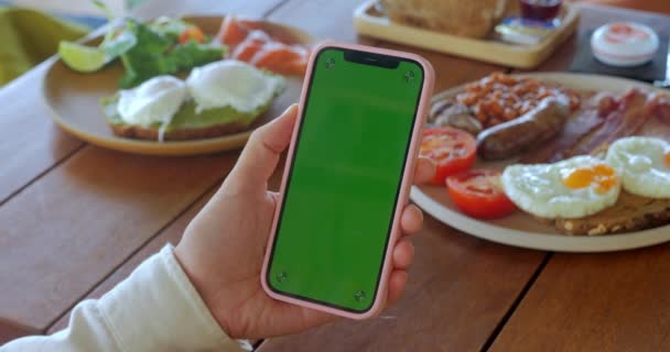 Kobieta Trzyma Smartfona Zielonym Ekranie Chroma Klucz Przy Stoliku Jedzeniem — Wideo stockowe