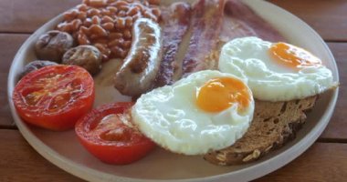 Sabah kahvaltısı yumurta, sosis, domates, jambon, fasulye, marul ve tost. Geleneksel İngiliz kahvaltısı tabakta, yakın plan. Amerikan barı ya da kafesi, fast food.
