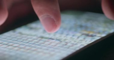 Yakın çekim erkek parmağı akıllı telefonun dokunmatik ekranında fotoğraf içeriğini değiştirir, geceleri zumlar ve kaydırır, akıllı telefon ekranı video ekranını aydınlatır.