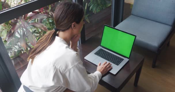 緑の画面でノートパソコン 女性の手を入力し トラックパッドにスクロールします 木製のテーブルに座って コーヒーショップで緑の画面を持つコンピュータを見て女性のバックビュー — ストック動画