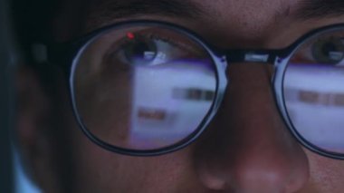 Close up male working at computer late at night, reflection in glasses of laptop screen. Double exposure monitor screen reflection, business male using laptop computer internet, surfing web pages.