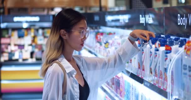 아시아의 소비자가 슈퍼마켓의 부분에서 샴푸를 안경을 아시아 여성은 슈퍼마켓에서 제품을 — 비디오