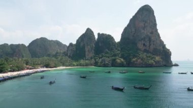 Railay plajı, hava manzarası. Cennet gibi Tayland Ao Nang plajının güzel kireçtaşı kayalıkları. Cennet Krabi manzaralı kaya formasyonuyla tatil köyü. Turistleri taşımak için birçok tekne sahilde yüzüyor..