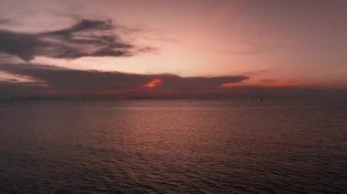 Okyanus suyunun üzerinde tropik kırmızı gün batımı, hava manzarası. Güneş deniz manzarasına yansıyor. Güneşli bir akşamda sakin bir su manzarası. Yaz tatili. Tropik tatil. Sinematik hava çekimi