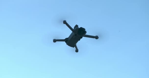 ドローンでの飛行と撮影 空にドローンクアッドコプター 青い空を背景にカメラを飛んでドローン 下からの眺めだ 上から写真やビデオを撮影するための近代的な技術 — ストック動画