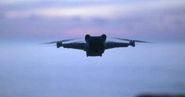 Günümüz kuadkopter insansız hava aracının silueti tatiller sırasında denizin arka planında. İnsansız hava aracı ile seyahat ederken video ve fotoğraf çekme kavramı. Modern teknoloji ve robotlar.