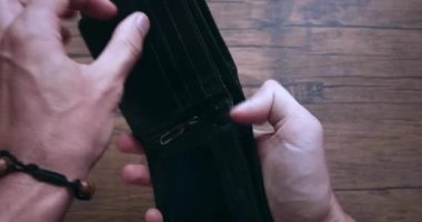 Yakın plan, erkek elleri parasız deri bir cüzdanı açıyor. Yoksulluk ve parasızlık kavramı. Konsept, cüzdanda para olmaması.