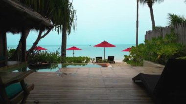 Sinematik çekim, yaz tatilleri için özel dinlenme amacıyla deniz kenarında kırmızı şemsiyeli küçük havuzu olan güzel bir özel otel odasıdır. Plaj tatili.