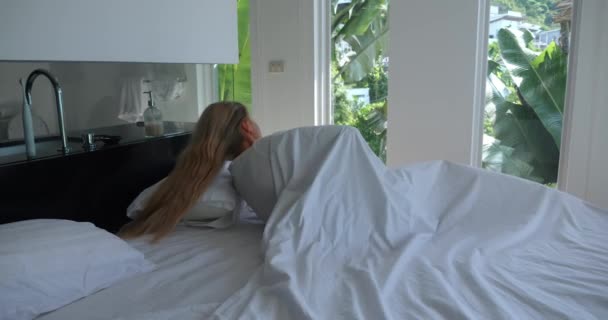 여자는 아침에 천년기 여인은 침대에 일어나서 게으름을 피우며 창문을 바라본다 — 비디오