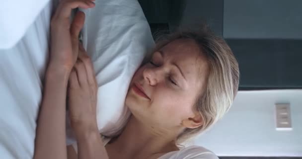 垂直ビデオの若い女性は寝室で眠り 枕の下からスマートフォンを取り出し 郵便物をチェックし ソーシャルネットワーク上のメッセージをチェックし 眠り続けます 社会的ネットワークへの依存の概念 — ストック動画