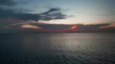 Güneş battıktan sonra okyanus suyunun üzerinde uçan hava aracı. Akşamlar denizin üzerinde uçuyor. Sinema insansız hava aracı akşam vakti karanlık deniz suyunun üzerinde gün batımından sonra güzel kızıl gökyüzü ile
