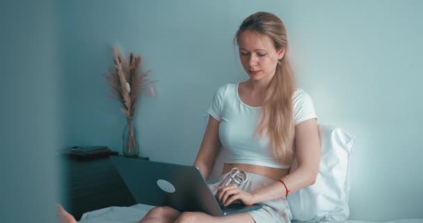 밀레니엄 여성은 침실에 누워서 컴퓨터를 이용하여 온라인으로 공부하고 있습니다 집에서 — 비디오