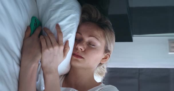 Νεαρή Ξανθιά Γυναίκα Κοιμάται Στην Κρεβατοκάμαρα Βγάζει Κινητό Της Τηλέφωνο — Αρχείο Βίντεο