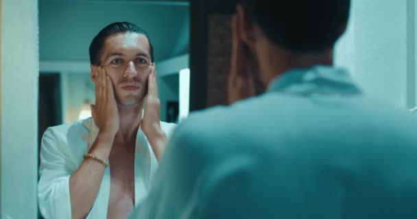 Jovem Aplicando Creme Hidratante Pele Rosto Olhando Espelho Banheiro Skincare — Vídeo de Stock