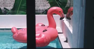 Pembe flamingo şişme havuz, lüks otel otelindeki havuzda yüzen oyuncak şilte. Lüks yüzme havuzunda şişirilebilir pembe flamingoyla seyahat konsepti. Yaz tatilleri