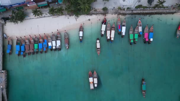 長い尾のボートを持つ熱帯の海のビーチの上の熱帯の風景は 桟橋近くの砂浜に海岸に立っています 島への観光客を取る地元のボートのトップビュー 熱帯夏休み — ストック動画