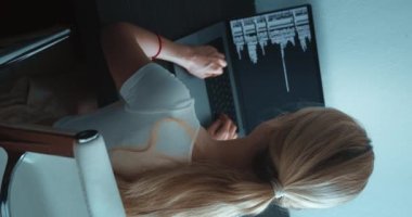 Dikey video, bilgisayar monitörüne bakan ve iş yerinde oturan kadın programcının dikey görüntüsü. Dizüstü bilgisayarla veri kodlaması yazan IT yazılım geliştiricisi