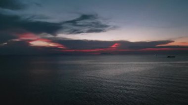 Drone sabah güneş doğmadan önce deniz suyunun üzerinde uçar. Olağanüstü doğal deniz manzarası. Güneş doğmadan önce turuncu bulutlarla güzel bir gündoğumu göğü, yeni bir günün başlangıcı. Sinematik hava görüntüsü.