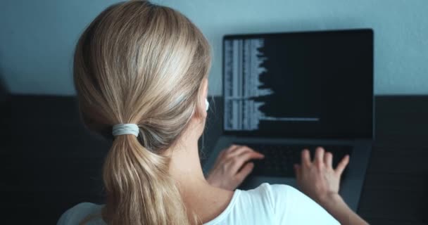 ラップトップコンピュータモニタとコーディングの前に座っている女性プログラマーの後部ビュー コンピュータで働く女性プログラマーのバックアップビューを閉じ オフィスの職場でコードを書き込みます — ストック動画