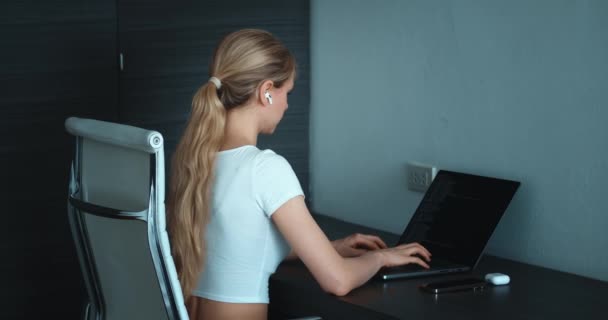 年轻女性自由职业数据科学家的后视镜在笔记本电脑的家庭编码编程中远程工作 在总公司电脑上工作的带耳机的后视镜金发女人 — 图库视频影像
