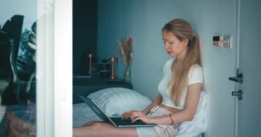 Milenyum kadın serbest yazar yatak odasında yatıp dizüstü bilgisayarla internette çalışıyor. İş kadını portresi, bilgisayarını kullanarak evden uzakta çalışan serbest bilgisayarcı.