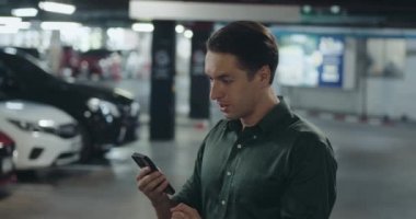 Heyecanlı yönetici piyango talihlisi telefonu tutar, park yerinde mutlu durur. Mutluluktan havalara uçan adam piyango kazananı konsepti mobil piyango talihlisini kutluyor..