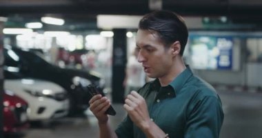 Şanslı genç bir adam. Erkek akıllı telefondan yeni mesajlar almış ve şanslı bir konsept adamı olduğunu söylemiş. Adam park yerinde durmuş, cep telefonundan iyi haberler okuyor.
