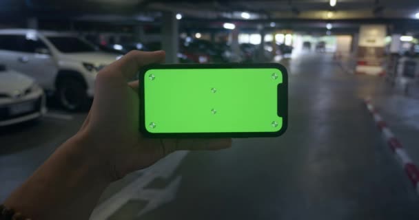 不认识的人拿着绿色屏幕电话 停在停车场的侧边 查看笔直的男性手拿着彩色键绿色屏幕电话模板 — 图库视频影像