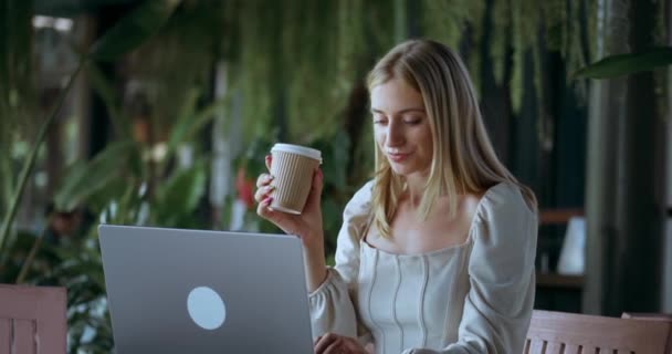 魅力的なブロンドのマネージャー女性のフリーランサーは コンピュータのラップトップの生活に入力します 女性はコーヒーを保持し 画面のノートパソコンの生活の概念に関する情報を研究する自信 女性は締め切りノートパソコンの生活を持っています — ストック動画
