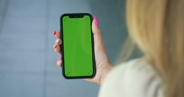 バックグラウンドストリートの垂直緑色の携帯電話でスマートフォンを握る女性の手 読書メッセージビジネス女性ストリートデバイスデジタル機器インターネット 緑色のスクリーン クロマ キーが付いているスマートフォン — ストック動画