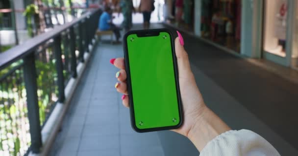 バックグラウンドストリートの垂直緑色のスクリーン携帯電話で携帯電話を保持している女性の手を閉じます 緑色のスクリーン クロマ キーが付いている携帯電話 ビジネス女性ストリートデバイスデジタル機器インターネット — ストック動画