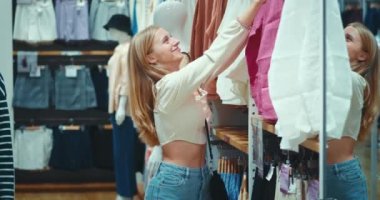 Alışverişçi kadın, sevdiği gömleklerin fiyatını gördü ve yerine dehşet içinde astı. Alışveriş merkezinde alışveriş yapan kişi kıyafet dener. Ev eşyaları için enflasyon maliyeti.