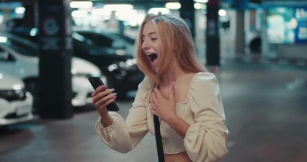 Étudiante Debout Dans Parking Détient Smartphone Lit Bonnes Nouvelles Concept — Video