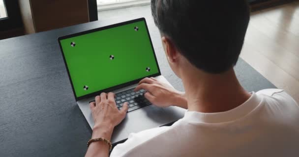 モックアップグリーンスクリーンディスプレイを搭載したコンピュータを使用したショットビジネスマン ビジネスマンはオフィスで働いている間緑色のスクリーン クロマのキーが付いているラップトップ コンピュータのキーボードのテキストをタイプします — ストック動画