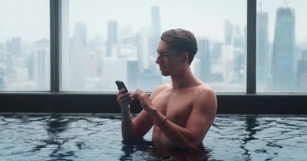 Zengin Adam Cep Telefonunu Kaydırırken Büyük Şehirde Çatıdaki Gökdelen Havuzunda — Stok video
