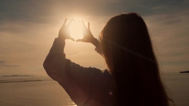 轮廓上的女性游客手在夕阳西下 海滨景致在暑假 在金色的红色日落时紧握着女人的手 阳光照射在里面的女人的手 享受海上暑假的概念 — 图库视频影像