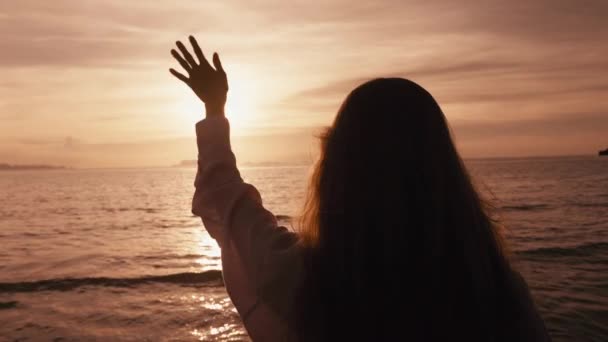 快乐的女性在日落时 在海上或海上用手指触摸太阳 在暑假里 快乐的年轻女子的手在与灿烂的阳光玩耍 女孩在日落时旅行 日落时海上自由的幸福 — 图库视频影像