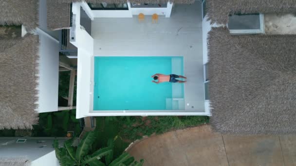 名目繁多的游客在夏季度假时跳入新鲜的游泳池水中 放松热带天堂的生活 水花四溅 夏天的概念 男子跳入游泳池的空中景观 — 图库视频影像