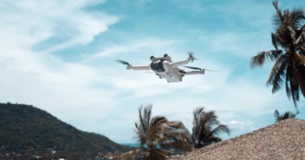 低速回転プロペラとビデオカメラを搭載したドローン飛行機 青空と手のひらを背景に飛行するドローンコピー機 夏の旅行中にコンテンツを作る — ストック動画