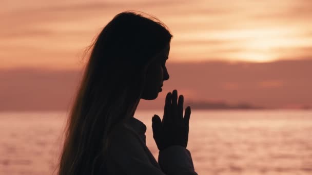 일몰이나 일출에 기도하는 여자의 초상화 기도를 여성은 해변에서 포즈를 취합니다 — 비디오