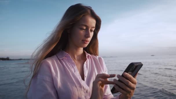 Mujer Joven Absorto Teléfono Inteligente Por Mar Mirando Pantalla Los — Vídeo de stock