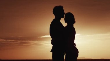 Erkek ve dişi, sabah deniz kenarında kucaklaşır. Gün doğumunda ya da günbatımında sevgi dolu bir ailenin silueti. Koca, sabah güneş doğarken karısına sarılır. Aile sevgisi kavramı