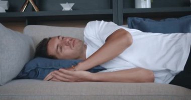 Bitkin düşmüş üzgün genç adam kanepeye düşüyor. Duygusuz üzgün erkek, yoğun çalışma ve depresyondan sonra yumuşak kanepede yorgun düşer. Evde enerji ve rahatlama sağlamak için uykuya dalıyor.