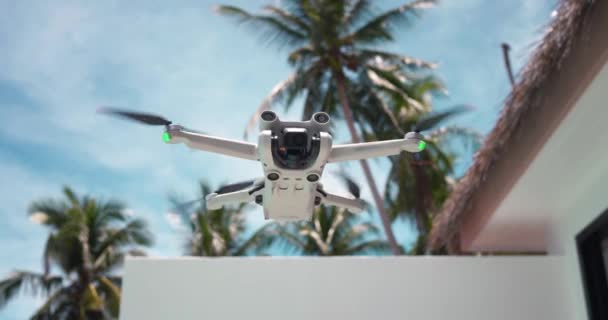 青い夏の空の背景 熱帯リゾートの手のひらに浮かぶ現代無人機の飛行機 旅行中に旅行ブロガーのコンテンツを撮影するための現代ドローンコピー — ストック動画