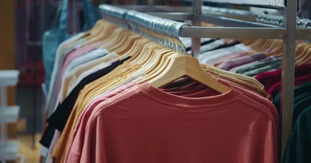 衣装のショッピングモールの選択 異なる色の服 持続可能なファッションコンセプト エコファッションのハンガーの綿のTシャツ 環境問題 服の合成材料の選択 — ストック動画