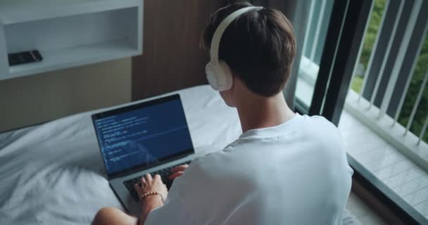 Οπίσθια Άποψη Άνθρωπος Ελεύθερος Επαγγελματίας Προγραμματιστής Ακουστικά Κάθεται Στο Κρεβάτι — Αρχείο Βίντεο