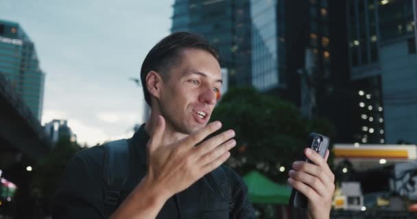 年轻人带着背包在大城市里散步 通过手机上的视频链接进行交流 谈论旅程 游客在大都市的街道上通过智能手机进行视频通话 — 图库视频影像